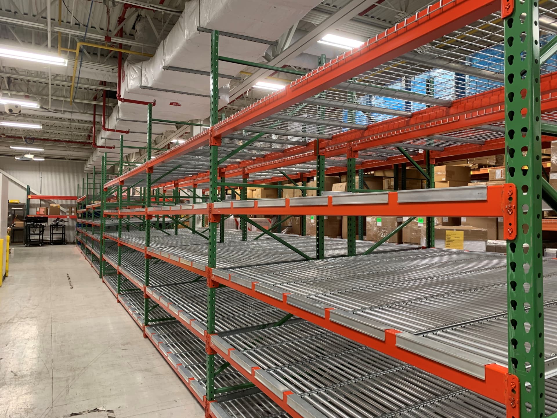 Carton flow rack levels with roller beds below pallet rack bays